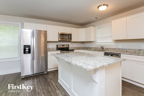 A kitchen with a stainless steel refrigerator and white cabinets.