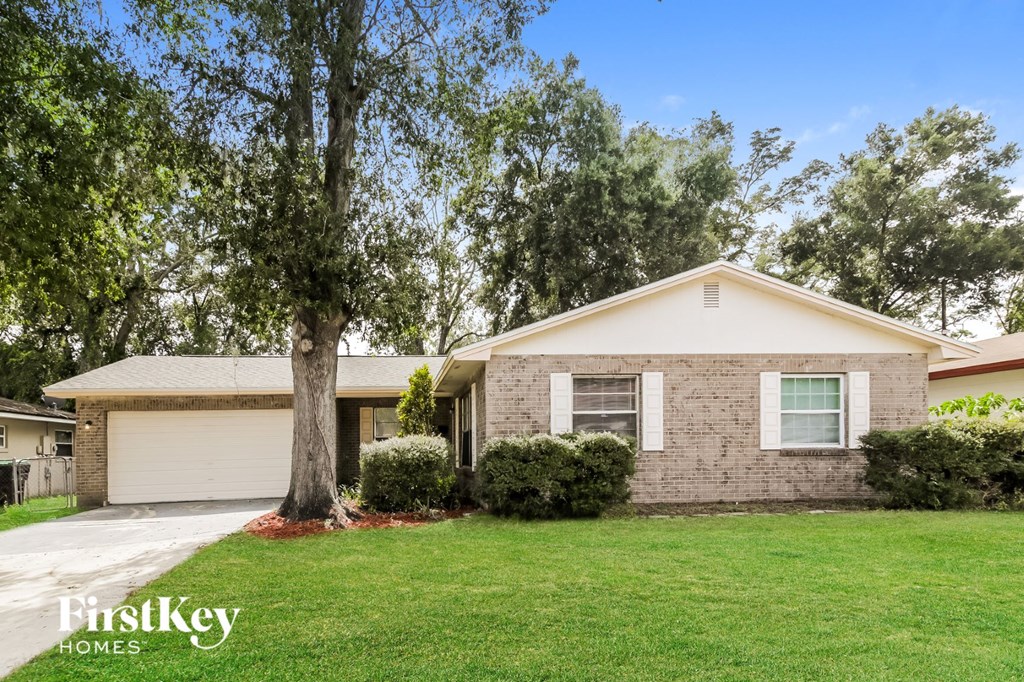 a small brick house with a lawn and a tree