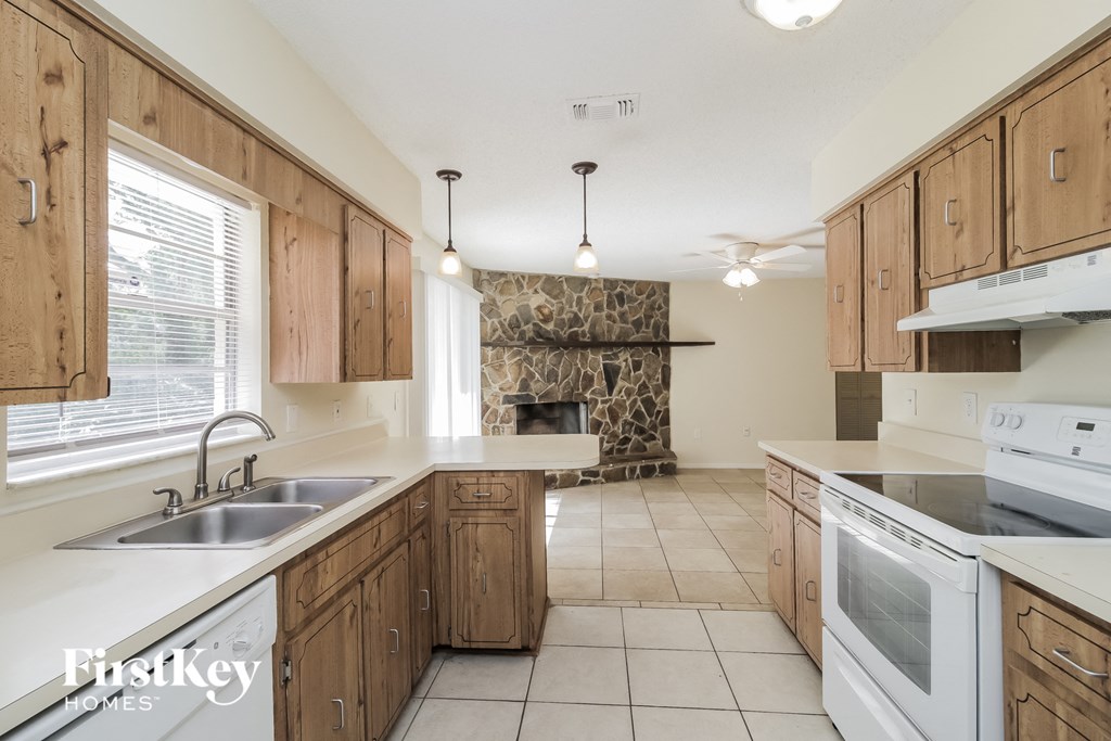 a kitchen with white appliances and wooden cabinets and a fireplace