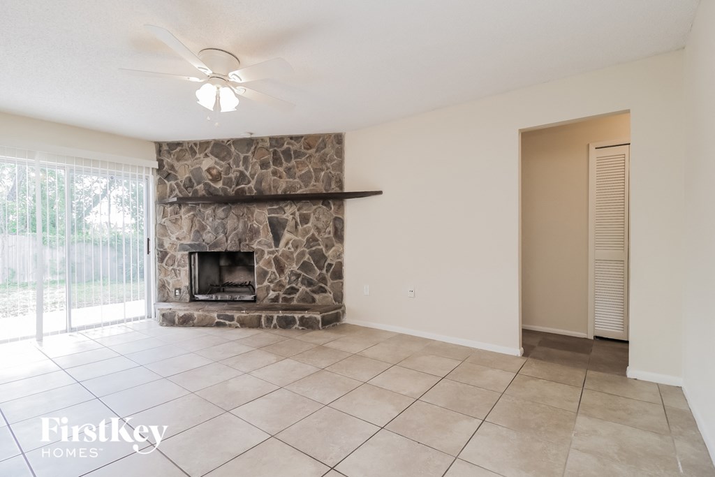 the living room has a stone fireplace and tile flooring