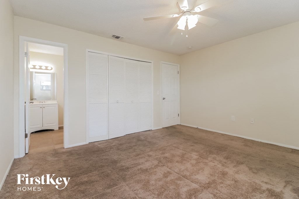an empty living room with carpet and a ceiling fan