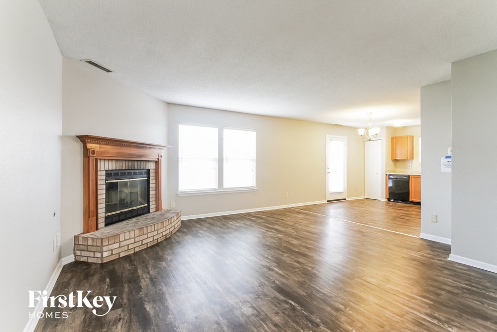 A spacious living room with a fireplace and wooden floors.