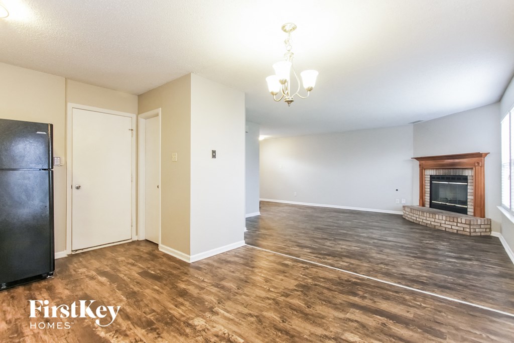 A large empty room with a fireplace and a chandelier.