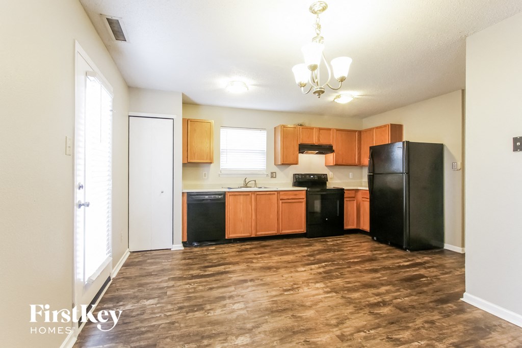 A kitchen with wooden floors and black appliances.
