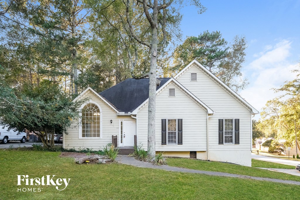 A white house with a black roof and a sign that says "FirstKey Homes".