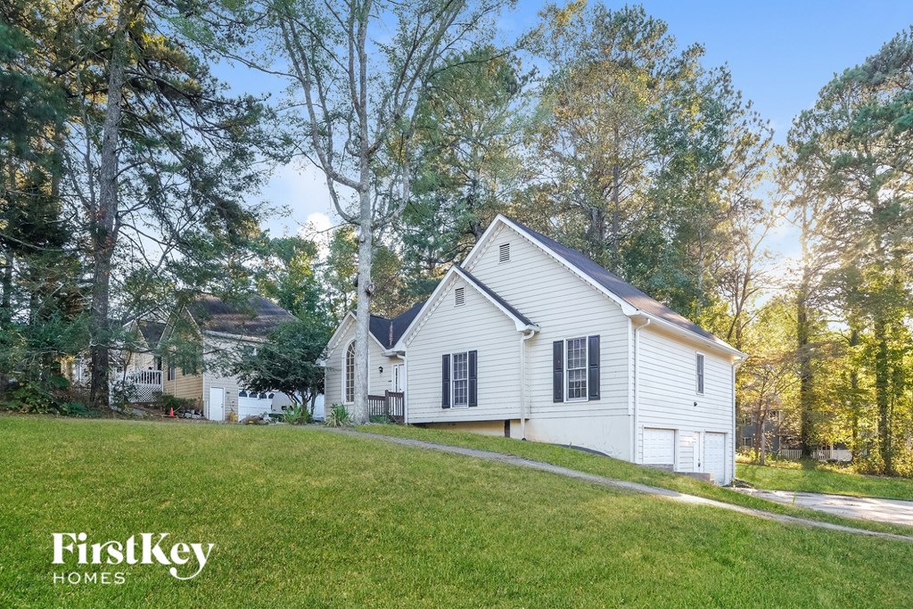 A white house with a green lawn in front of it.