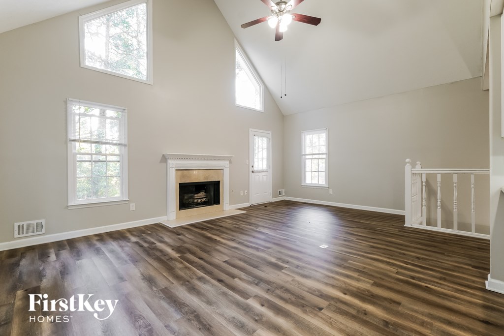 A spacious room with wooden floors and a fireplace is on display.