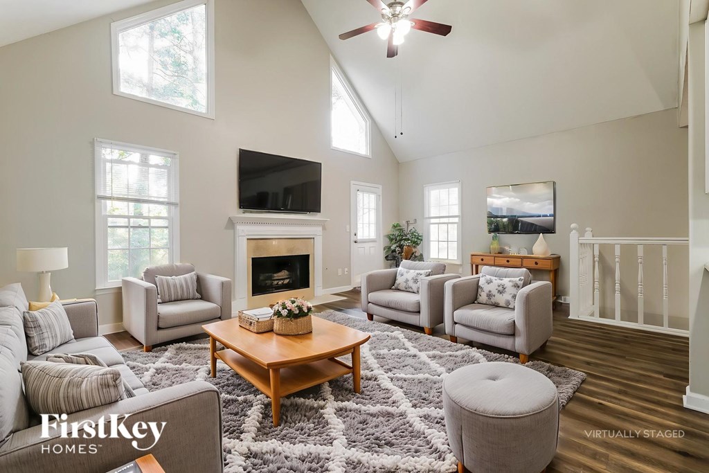 A living room with a fireplace and a ceiling fan.
