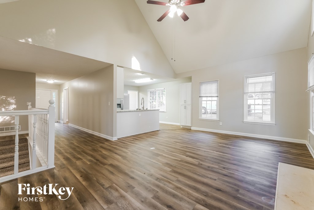 A spacious room with wooden floors and a ceiling fan.