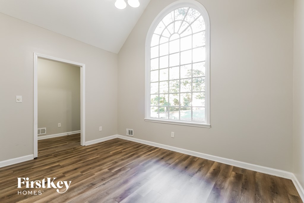 A room with a large arched window and wooden flooring.