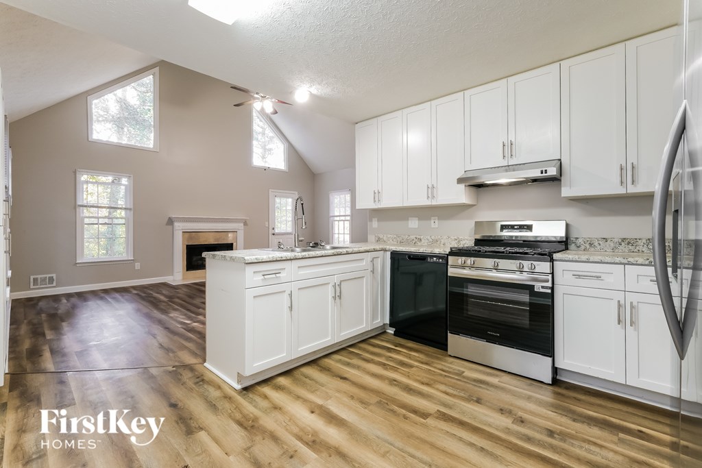 A kitchen with wooden floors and white cabinets.