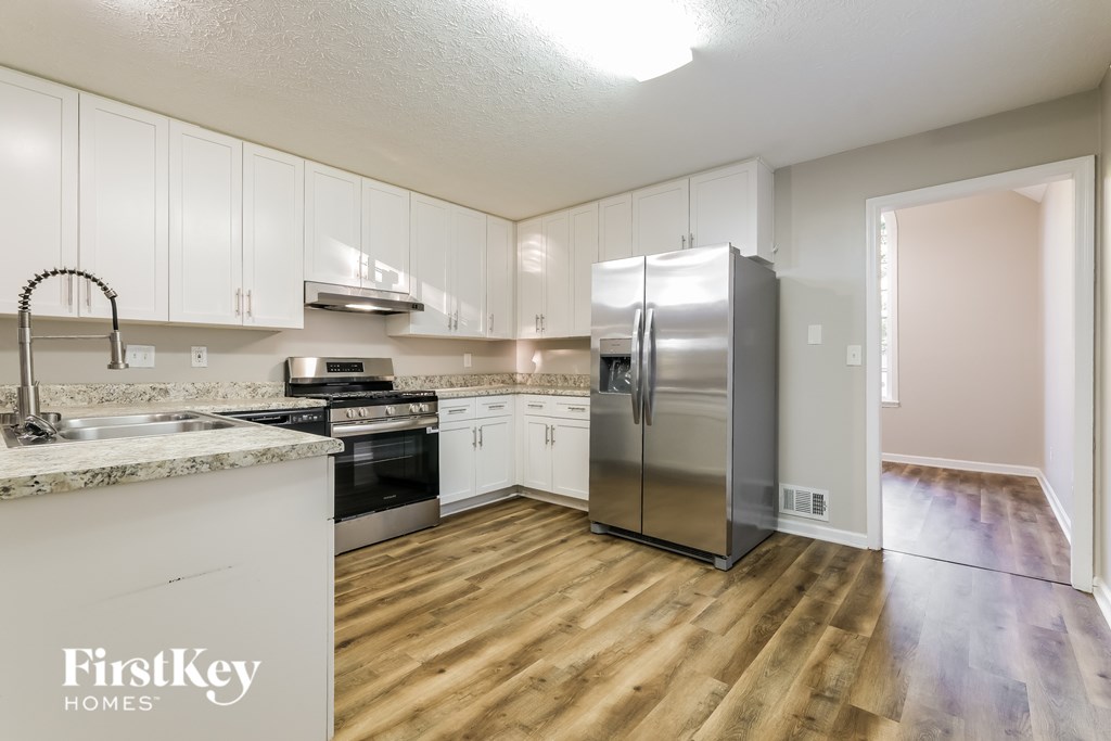 A kitchen with wooden floors and a refrigerator.