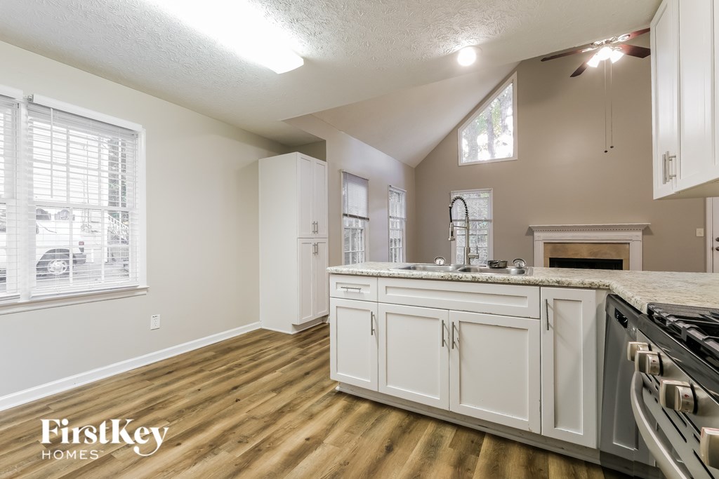 A kitchen with wooden floors and white cabinets.