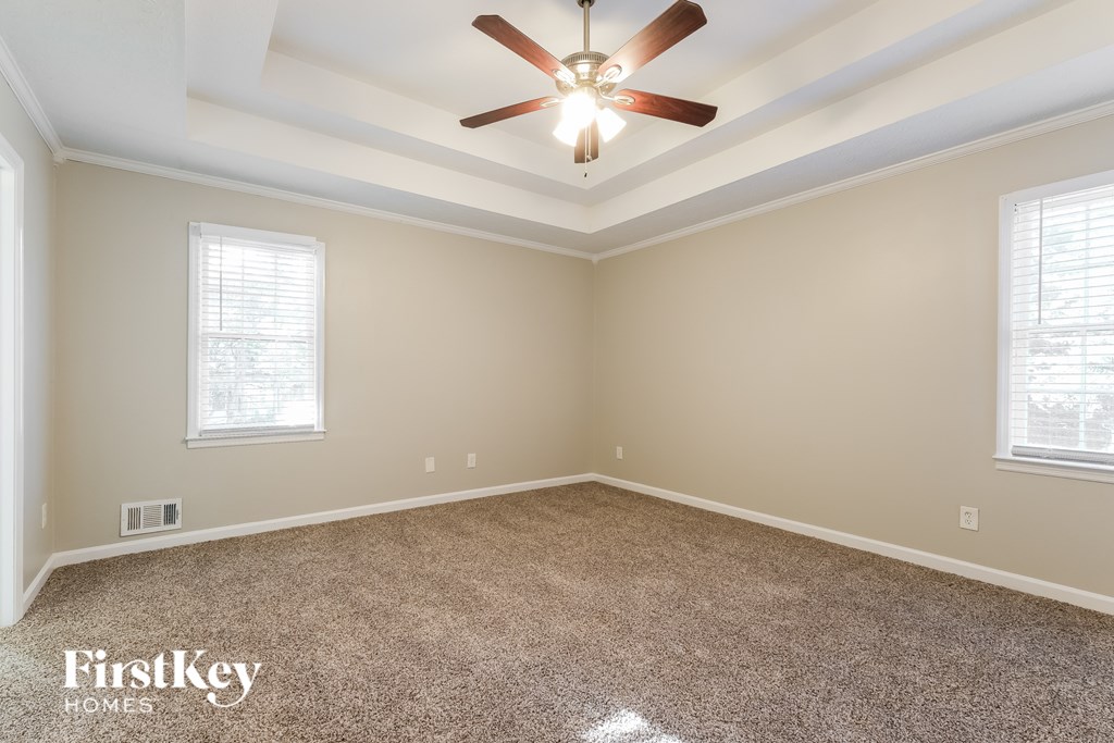 A room with a ceiling fan and two windows.