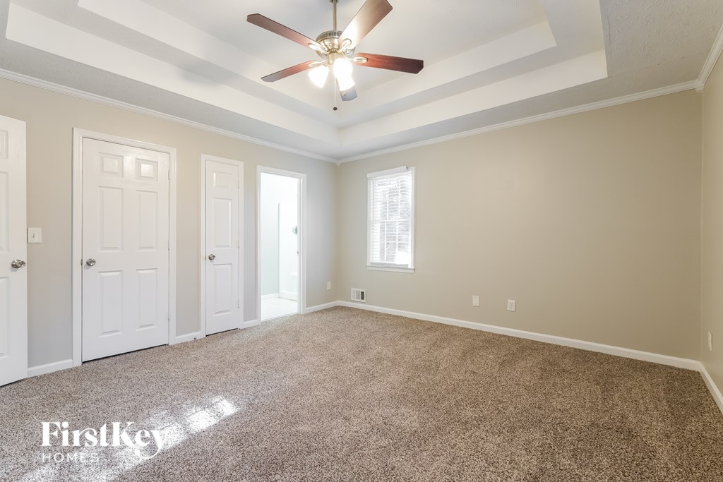 A spacious room with a ceiling fan and carpeted floor.