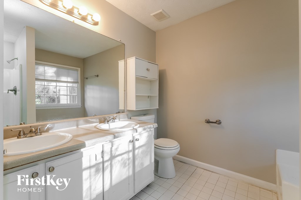 A bathroom with a white toilet and a mirror above the sink.