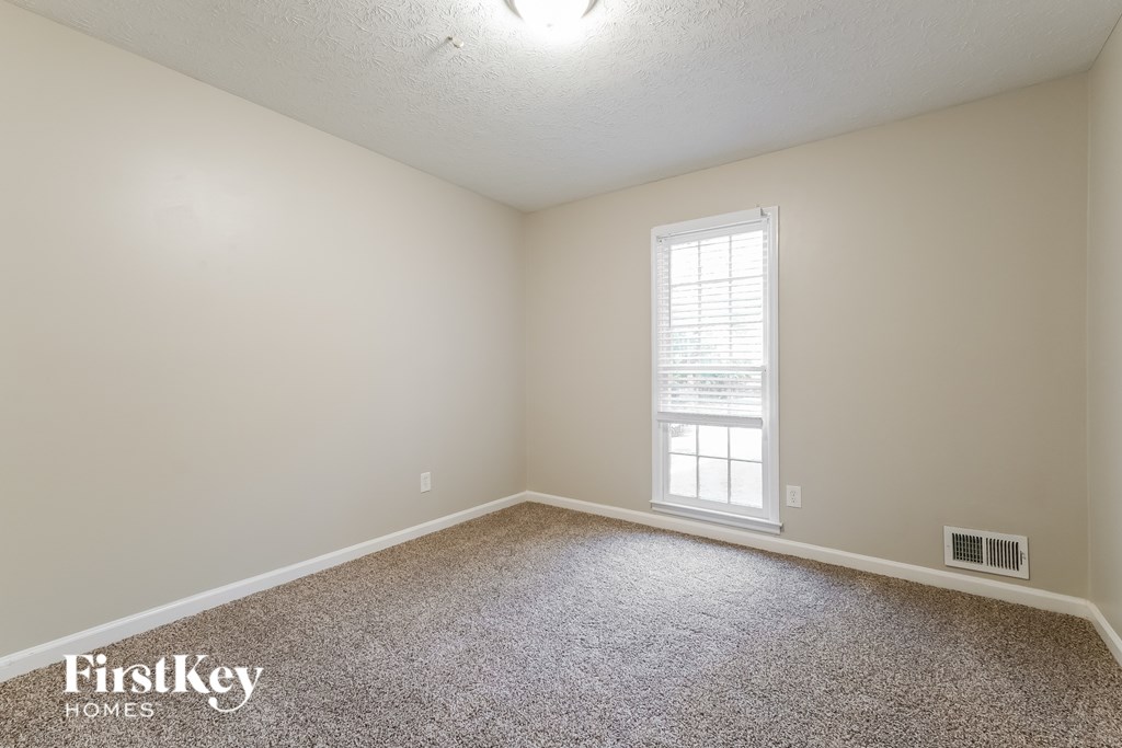 A room with a window and a carpeted floor.