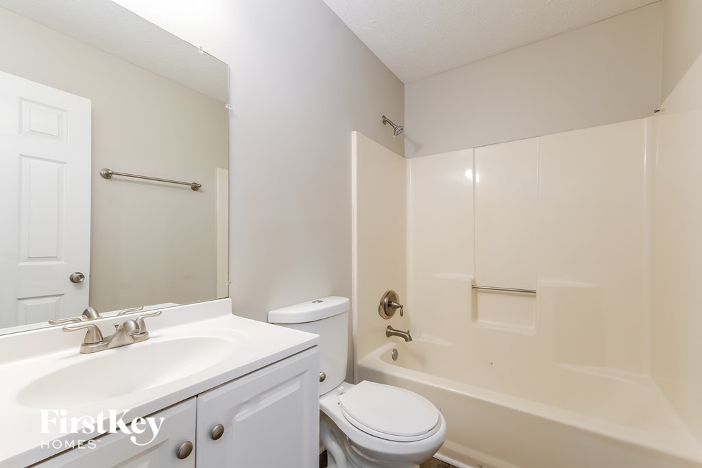 A white bathroom with a toilet, sink, and bathtub.