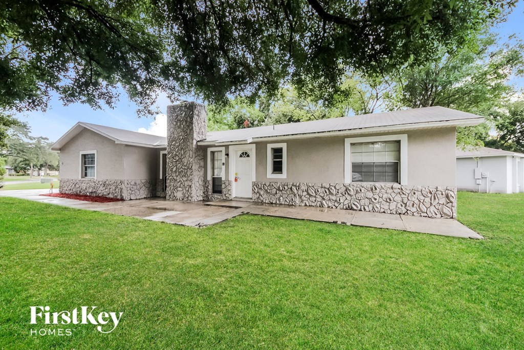 a white house with a lawn and a tree