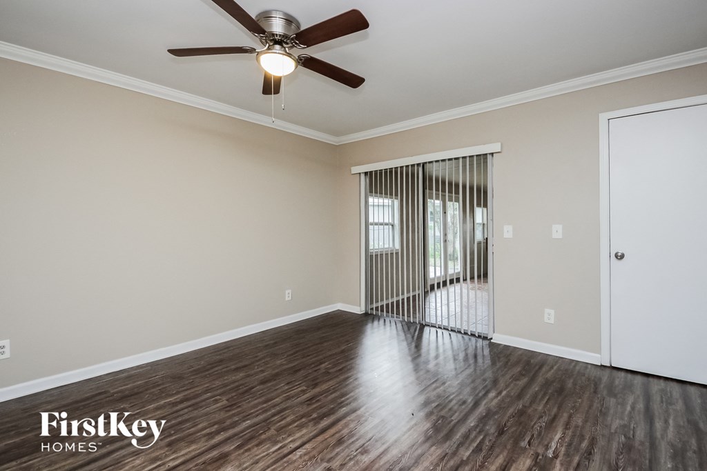 an empty living room with wood flooring and a ceiling fan