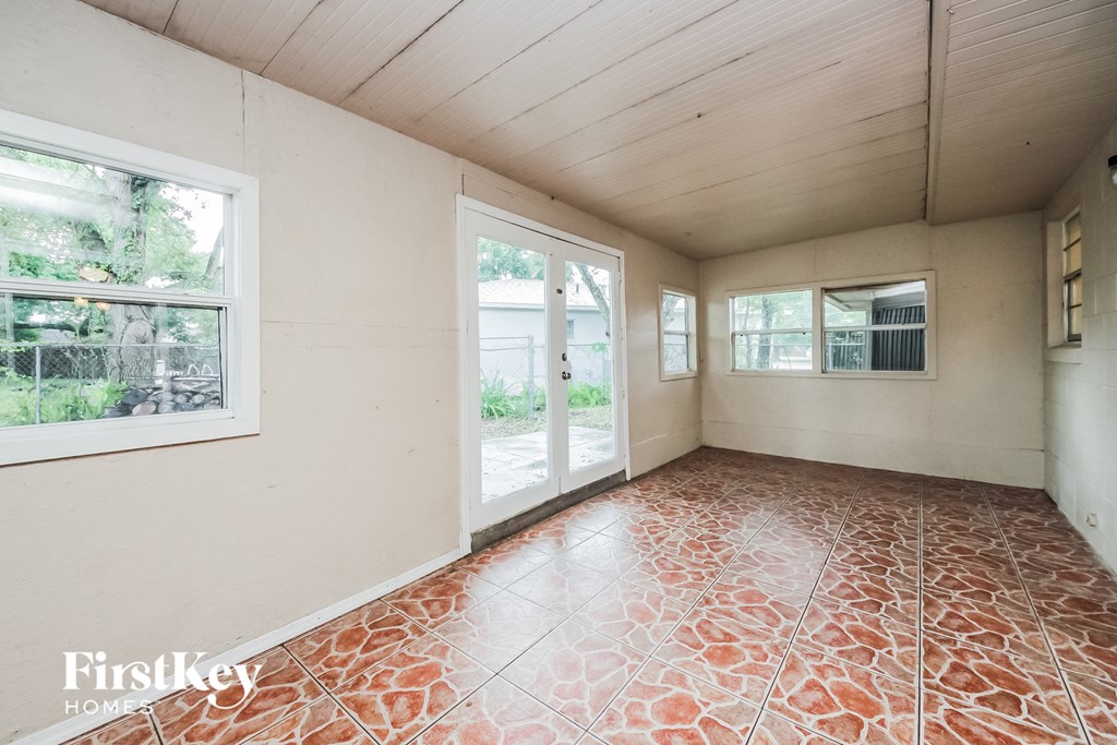 an empty living room with large windows and a tile floor