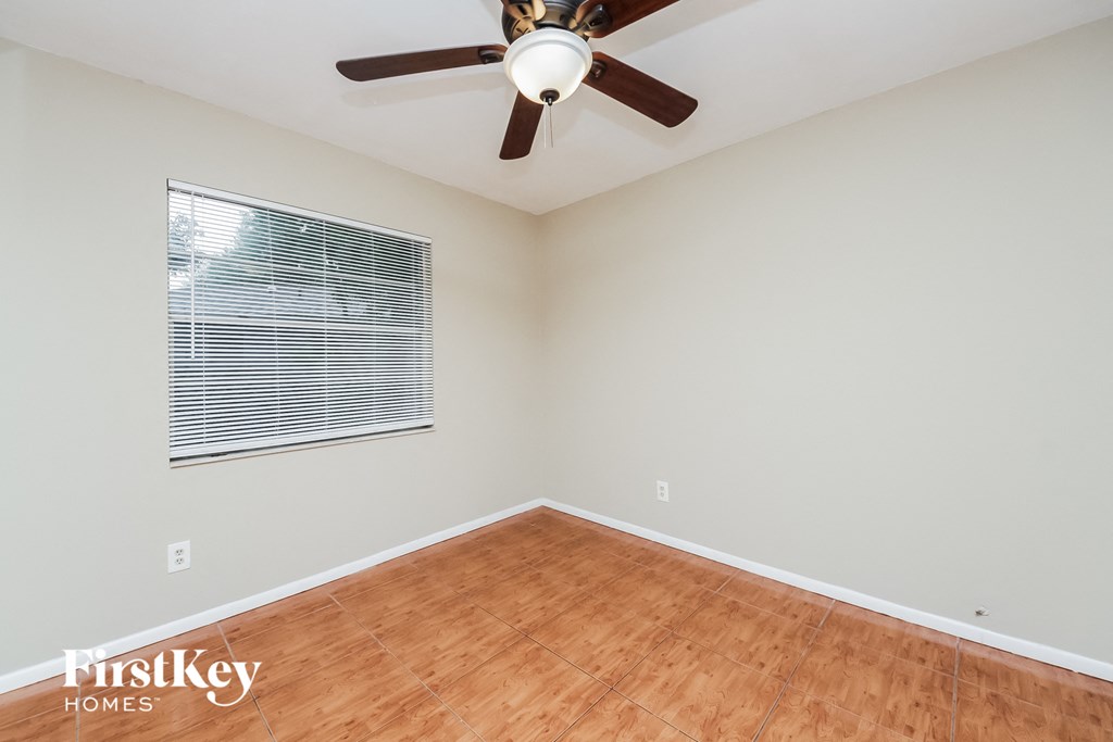 an empty room with a ceiling fan and a window
