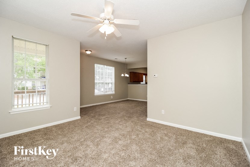 a spacious living room with carpet and a ceiling fan