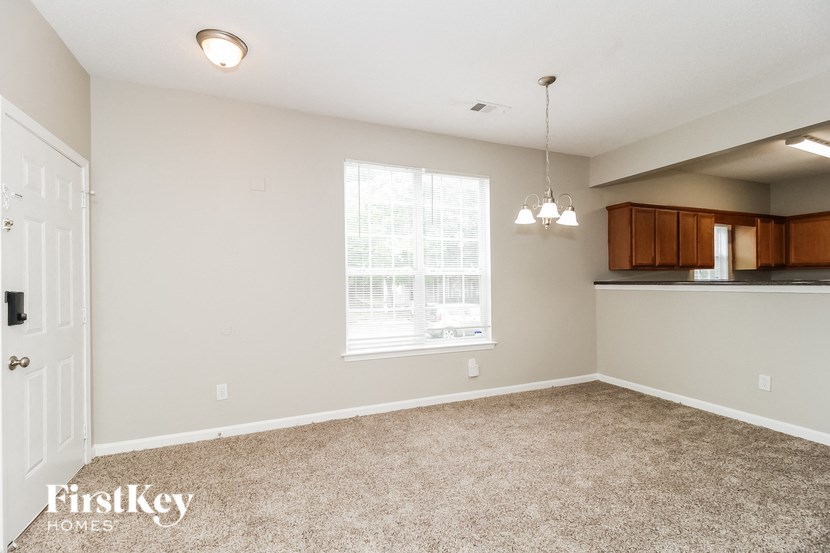 an empty living room with a window and a kitchen