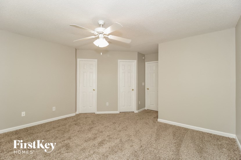a spacious living room with carpet and a ceiling fan