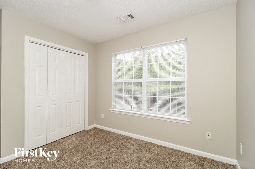 a bedroom with carpet and a large window and a white door