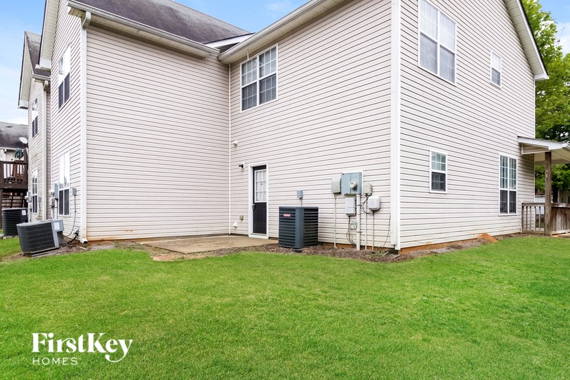 the side of a white house with a lawn and a backdoor