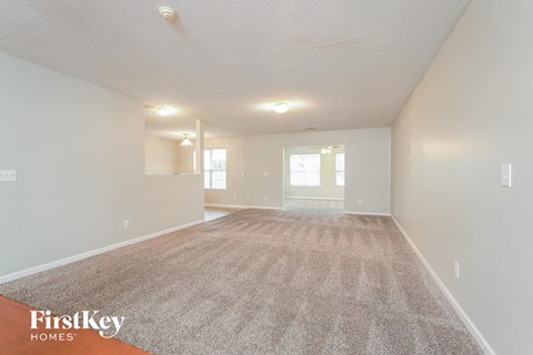 a spacious living room with carpet and white walls