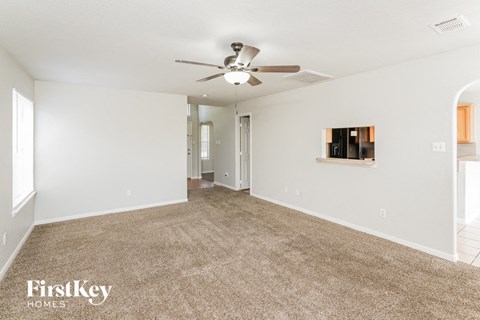 A spacious room with a carpeted floor and a ceiling fan.