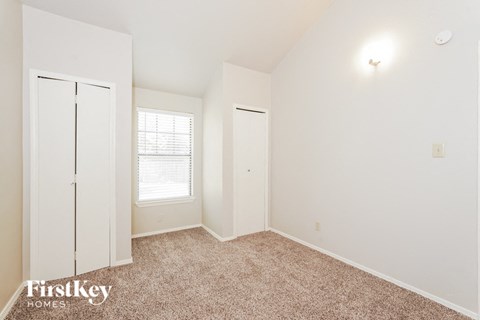 a bedroom with white walls and carpet and a window
