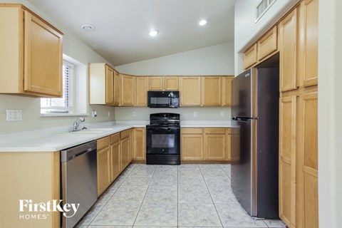 A kitchen with wooden cabinets and a black refrigerator.