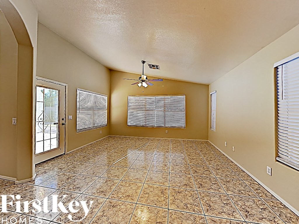 A spacious room with a tile floor and a ceiling fan.