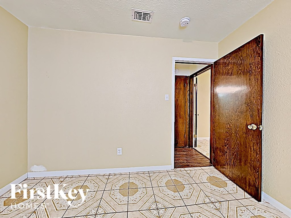 a hallway with a wooden door and a tiled floor