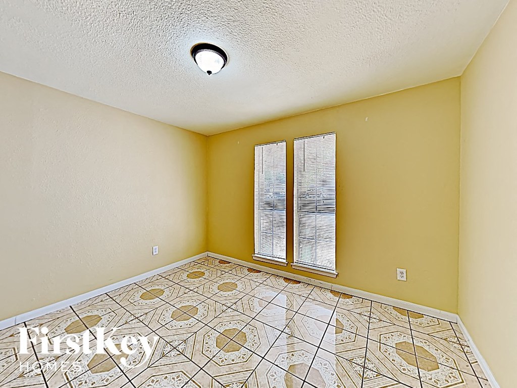 an empty living room with a large windows and a tiled floor