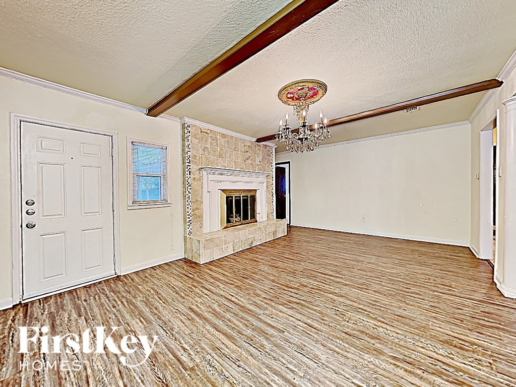 an empty living room with a fireplace and a chandelier