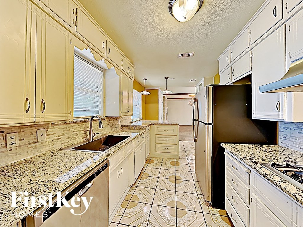 a kitchen with white cabinets and a sink and a refrigerator