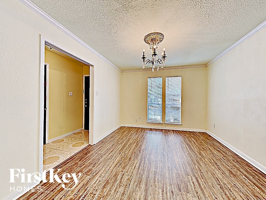 an empty living room with wood floors and a chandelier