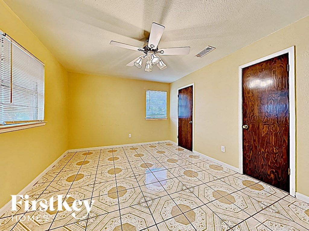 an empty bedroom with a ceiling fan and a door