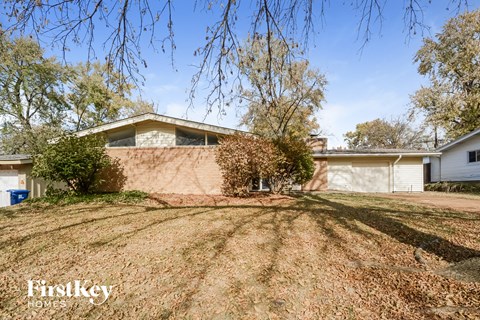A house with a brown wall and a white garage door is for sale.
