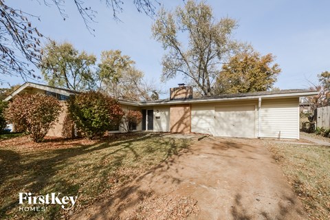 A house with a driveway and trees in the background.