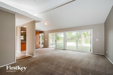 A spacious room with a carpeted floor and a sliding glass door leading to a garden.