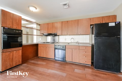 A kitchen with wooden cabinets and a black fridge.