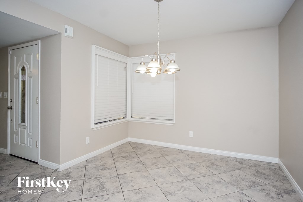 an empty dining room with white blinds and a chandelier