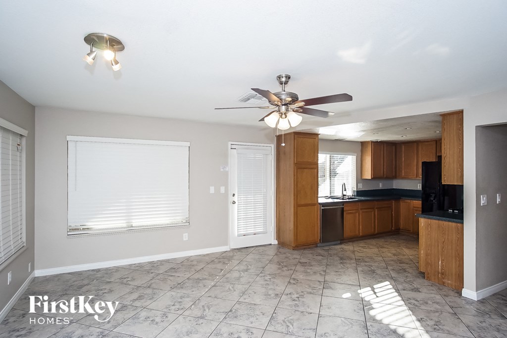 an empty kitchen with a ceiling fan and a window