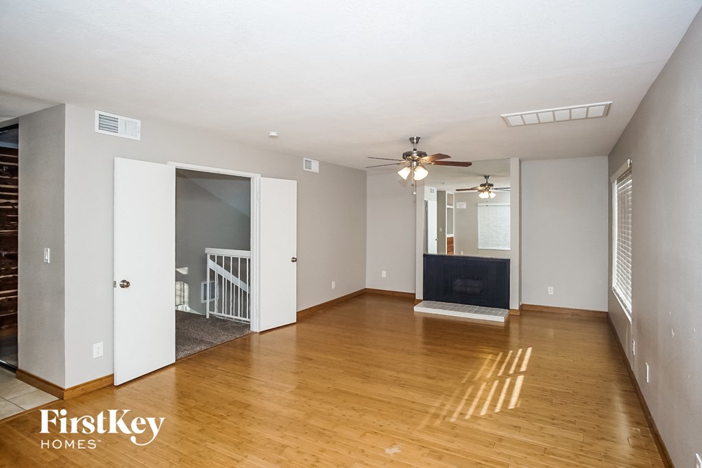an empty living room with hardwood floors and a ceiling fan