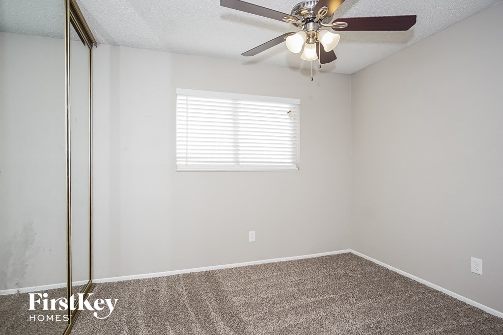 the living room of an empty home with a ceiling fan